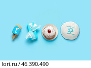 Hanukkah composition with donut, kipa, gift box and dreidel on blue background. Стоковое фото, фотограф Pixel_shot / Фотобанк Лори