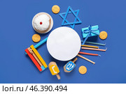 Hannukah composition with blank greeting card, candles, dreidels, gift box and donut on blue background. Стоковое фото, фотограф Pixel_shot / Фотобанк Лори
