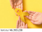 Women holding yellow ribbon on color background, closeup. Sarcoma concept. Стоковое фото, фотограф Pixel_shot / Фотобанк Лори