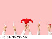 Doctor's hands with female uterus, pregnancy test and pap test tools on pink background. Стоковое фото, фотограф Pixel_shot / Фотобанк Лори