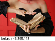 Evil young witch with spell book on color background. Стоковое фото, фотограф Pixel_shot / Фотобанк Лори