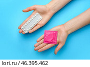 Female hands with wrapped condom and birth control pills on color background. Стоковое фото, фотограф Pixel_shot / Фотобанк Лори