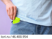 Man putting condom into pocket of jeans on color background, closeup. Стоковое фото, фотограф Pixel_shot / Фотобанк Лори