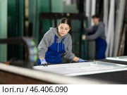 Girl glazer employee in blue overall works in glass processing shop. Стоковое фото, фотограф Яков Филимонов / Фотобанк Лори