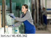 Girl glazer employee in blue overall works in glass processing shop. Стоковое фото, фотограф Яков Филимонов / Фотобанк Лори