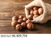 Bag with tasty macadamia nuts on wooden table. Стоковое фото, фотограф Pixel_shot / Фотобанк Лори