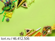Frame made of Hamantaschen cookies, carnival masks and rattles for Purim holiday on green background. Стоковое фото, фотограф Pixel_shot / Фотобанк Лори