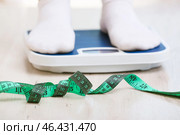 Skinny woman with measuring tape standing on floor scales. Concept of anorexia. Стоковое фото, фотограф Pixel_shot / Фотобанк Лори