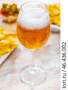 Glass of chilled frothy beer with snacks - potato chips and pickled olives. Стоковое фото, фотограф Яков Филимонов / Фотобанк Лори