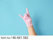 Рука в защитной перчатке показывает жест рогов дьявола на цветном фоне. Стоковое фото, фотограф Pixel_shot / Фотобанк Лори