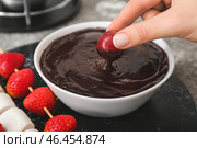 Женщина, окуная вкусный виноград в миску с шоколадным фондю на столе, крупным планом. Стоковое фото, фотограф Pixel_shot / Фотобанк Лори