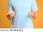 Молодой человек с пероральной эректильной дисфункцией лекарства и презерватив на цветном фоне. Стоковое фото, фотограф Pixel_shot / Фотобанк Лори