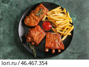 Тарелка с вкусными жареными ребрышками и картофелем фри на столе. Стоковое фото, фотограф Pixel_shot / Фотобанк Лори