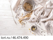 Сита с сушеной ромашкой и чайными листьями на белом деревянном столе. Стоковое фото, фотограф Pixel_shot / Фотобанк Лори