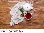 Салфетка с сухим прессованным чаем пуэр, чашка и чайник на деревянном фоне. Стоковое фото, фотограф Pixel_shot / Фотобанк Лори