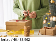 Женщина упаковывает рождественский подарок за столом, крупным планом. Стоковое фото, фотограф Pixel_shot / Фотобанк Лори