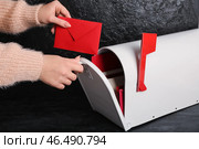 Женщина берет письмо из почтового ящика на темном фоне. Празднование Дня святого Валентина. Стоковое фото, фотограф Pixel_shot / Фотобанк Лори