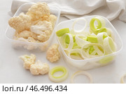 Пластиковые контейнеры с цветной капустой и луком-пореем на светлом фоне, крупным планом. Стоковое фото, фотограф Pixel_shot / Фотобанк Лори