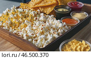 Delicious popcorn and nachos with various sauces and cheese powder. Стоковое AI-видео, аниматор Юрий Поздников / Фотобанк Лори