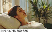 Woman relaxing on couch enjoying sunlight, peaceful home atmosphere. Стоковое AI-видео, аниматор Юрий Поздников / Фотобанк Лори