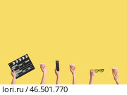 Руки, держащие ведра с попкорном, киношный щиток, пульт от телевизора и 3D очки на желтом фоне. Стоковое фото, фотограф Pixel_shot / Фотобанк Лори