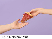 Женская рука, подающая вкусный кусок пиццы на лиловом фоне. Стоковое фото, фотограф Pixel_shot / Фотобанк Лори