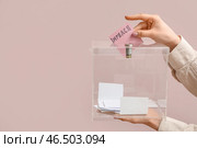 Женщина опускает бюллетень с надписью ИМПИЧМЕНТ в урну для голосования на розовом фоне. Стоковое фото, фотограф Pixel_shot / Фотобанк Лори