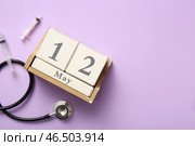 Календарь со стетоскопом и шприцами на сиреневом фоне. Международный день медсестры. Стоковое фото, фотограф Pixel_shot / Фотобанк Лори