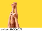 Молодая афроамериканка наносит солнцезащитный крем на ногу на фоне желтого цвета. Стоковое фото, фотограф Pixel_shot / Фотобанк Лори