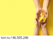 Женщина, держащая жёлтую ленту на цветном фоне. Концепция саркомы. Стоковое фото, фотограф Pixel_shot / Фотобанк Лори
