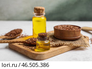 Деревянная доска с бутылками льняного масла и семенами на светлом столе. Стоковое фото, фотограф Pixel_shot / Фотобанк Лори