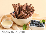 Чаши вкусные шоколадные вафельные трубочки, черника и сгущенное молоко на бежевом фоне. Стоковое фото, фотограф Pixel_shot / Фотобанк Лори