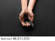 Женщина держит черную траурную ленту на темном фоне. Стоковое фото, фотограф Pixel_shot / Фотобанк Лори