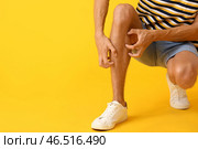 Молодой человек чешется на цветном фоне. Стоковое фото, фотограф Pixel_shot / Фотобанк Лори
