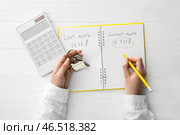 Женщина делает расчет арендной платы и держит ключ с брелком в форме дома на белом деревянном фоне. Стоковое фото, фотограф Pixel_shot / Фотобанк Лори