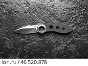Складной перочинный нож с прорезиненной рукоятью на черном фактурном фоне. Стоковое фото, фотограф Pixel_shot / Фотобанк Лори
