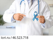 Мужчина-уролог указывает на синюю ленту в клинике, крупным планом. Концепция повышения осведомленности о раке простаты. Стоковое фото, фотограф Pixel_shot / Фотобанк Лори