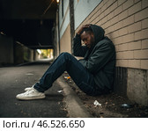Бездомный, грустный и уставший мужчина сидит ночью у стены. Стоковое AI-изображение, AI-художник Виталий Самсонов / Фотобанк Лори