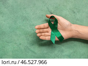 Женская рука, держащая зелёную ленту на цветном фоне. Концепция национального месяца осведомленности о церебральном параличе. Стоковое фото, фотограф Pixel_shot / Фотобанк Лори