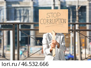 Женщина держит плакат с текстом ОСТАНОВИТЬ КОРРУПЦИЮ на открытом воздухе. Стоковое фото, фотограф Pixel_shot / Фотобанк Лори