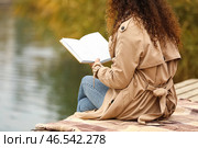 Молодая афроамериканка читает книгу с пустыми страницами на пледе у реки, крупным планом. Стоковое фото, фотограф Pixel_shot / Фотобанк Лори