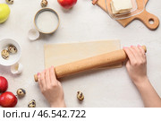 Женщина раскатывает тесто для яблочного штруделя на белом фоне. Стоковое фото, фотограф Pixel_shot / Фотобанк Лори