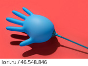 Надутая медицинская перчатка на красном фоне. Стоковое фото, фотограф Pixel_shot / Фотобанк Лори