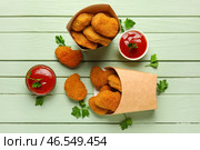 Бумажные коробки вкусных наггетсов с кетчупом на зеленом деревянном фоне. Стоковое фото, фотограф Pixel_shot / Фотобанк Лори