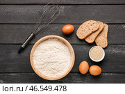 Чаша с пшеничной мукой, яйцами, кусочками хлеба и венчиком на черном деревянном столе. Стоковое фото, фотограф Pixel_shot / Фотобанк Лори