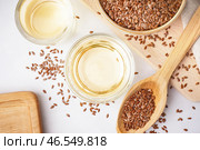 Миска, стакан с льняным маслом и ложкой семян на белом фоне. Стоковое фото, фотограф Pixel_shot / Фотобанк Лори