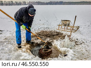 Farmer extracting sapropel from a freshwater lake through an ice hole, using a basket and sled, for use as organic fertilizer. Стоковое фото, фотограф Владимир Григорьев / Фотобанк Лори