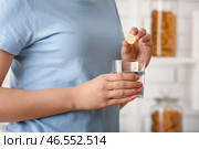 Женщина кладет шипучий таблетку в стакан с водой. Стоковое фото, фотограф Pixel_shot / Фотобанк Лори