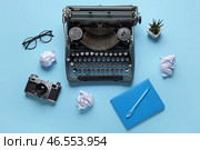Винтажная печатная машинка с камерой, очками и блокнотом на голубом фоне. Стоковое фото, фотограф Pixel_shot / Фотобанк Лори