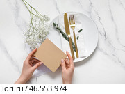 Женщина держит пустое пригласительное открытие у сервированного стола с цветами гипсофилы. Стоковое фото, фотограф Pixel_shot / Фотобанк Лори